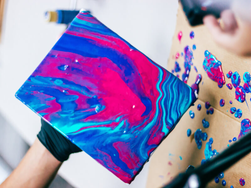 Paint flows over canvas as someone makes fluid art